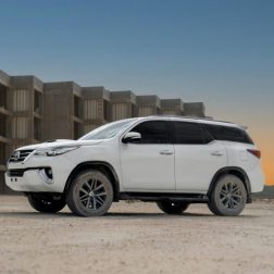 A white Toyota SUV parked in front of a concrete structure during sunset, highlighting its rugged design.